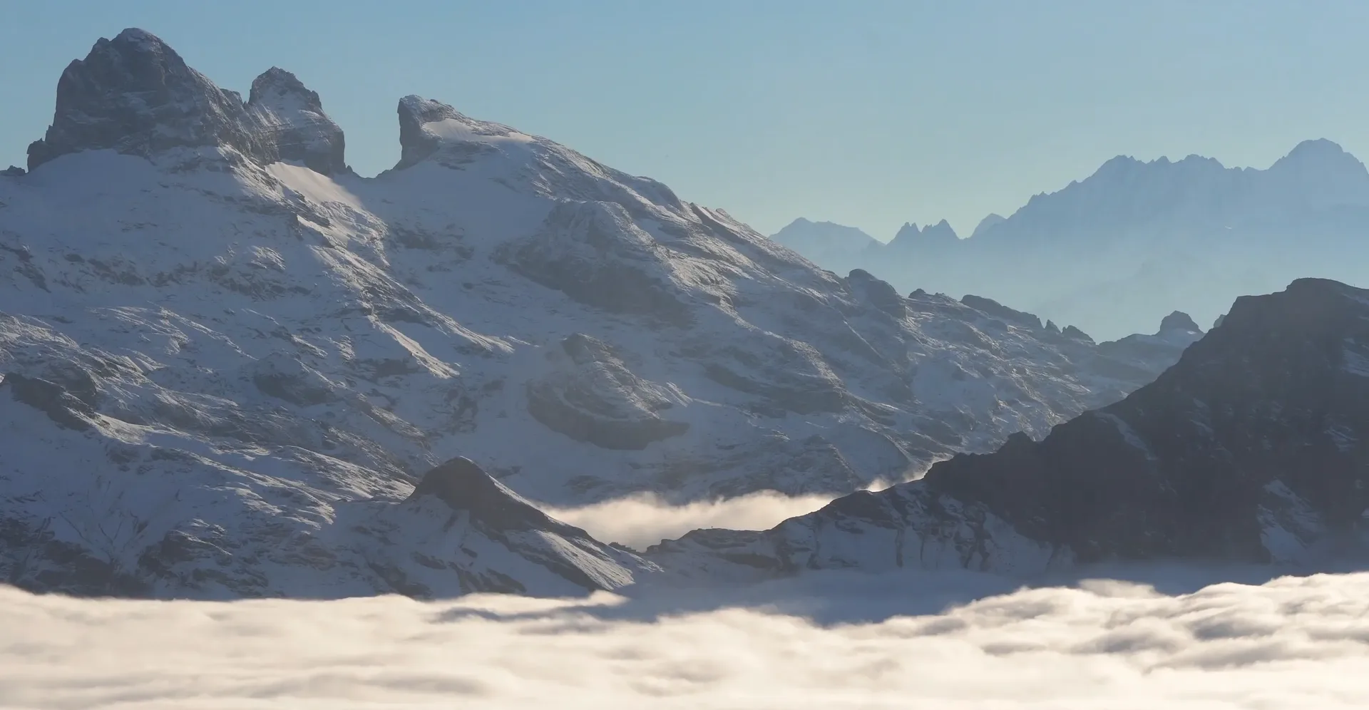 Snow-covered mountain ridge above a sea of clouds